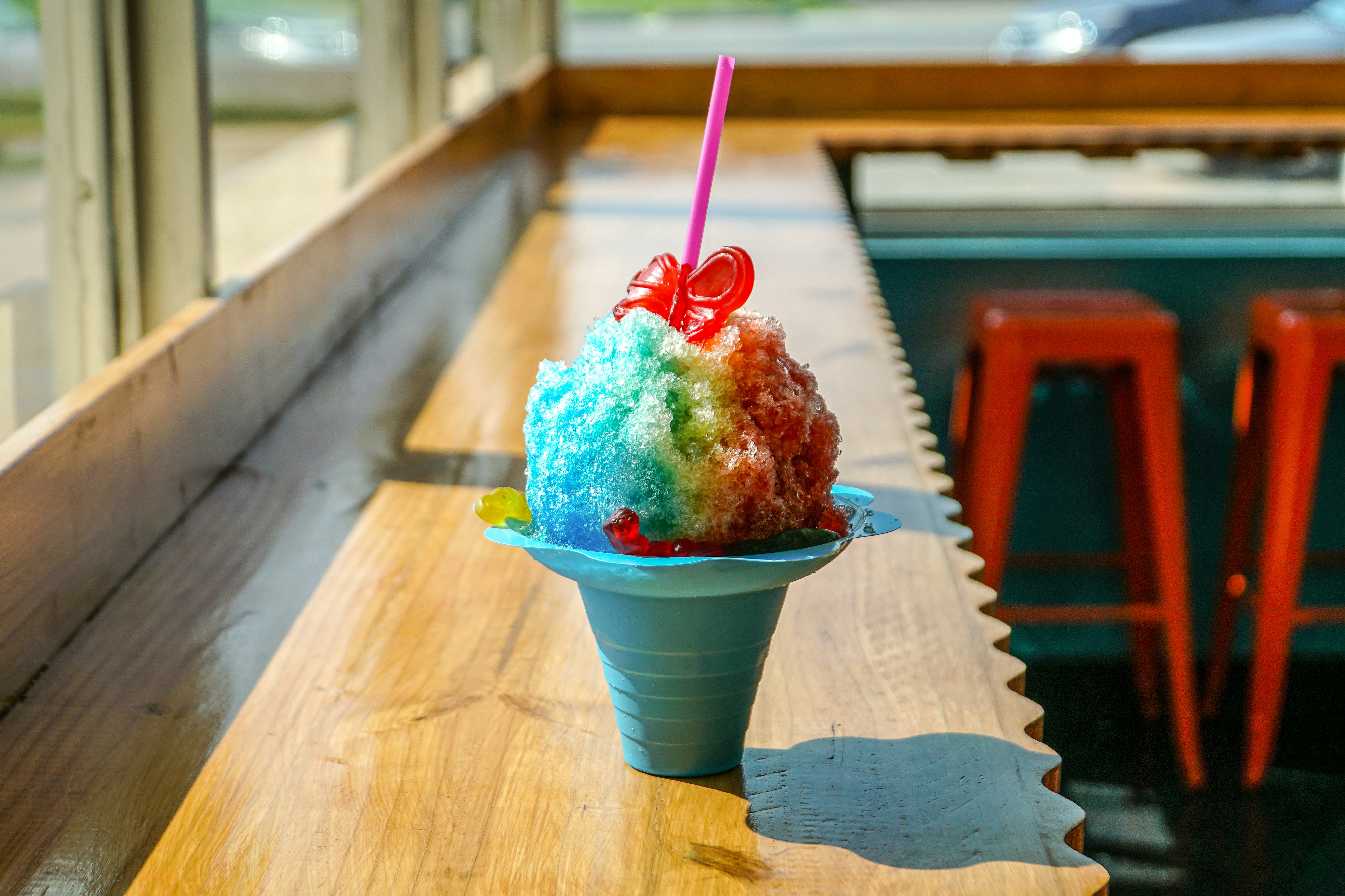 Classic party snow cones in paper cups with bright blue raspberry, cherry, and grape syrups
